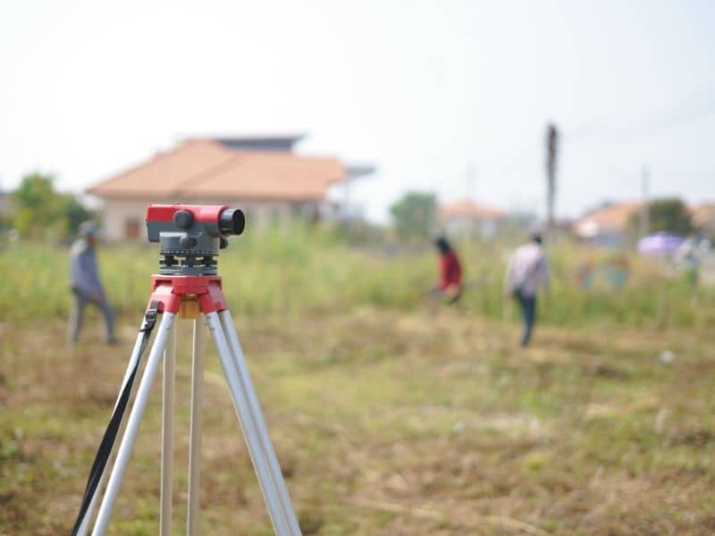 Survey crew working on a residential property while survey equipment is set up during a land survey